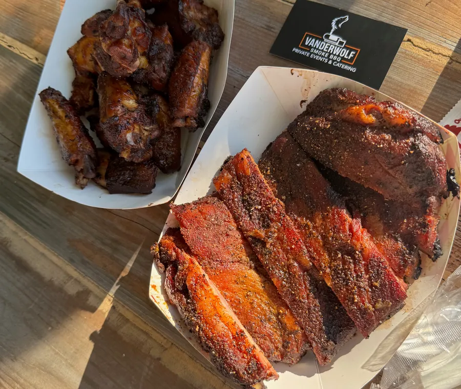 A catered barbecue spread of wings and sliced brisket, ready to serve
