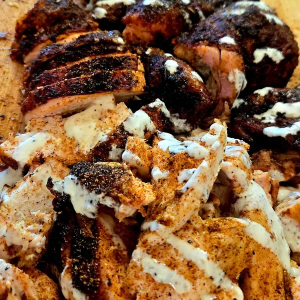 Sliced smoked chicken drizzled with Alabama white sauce