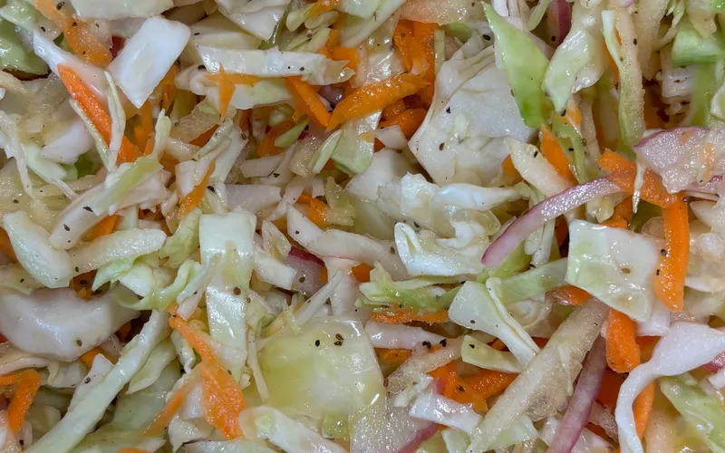A pulled pork sandwich piled high with coleslaw and pickles