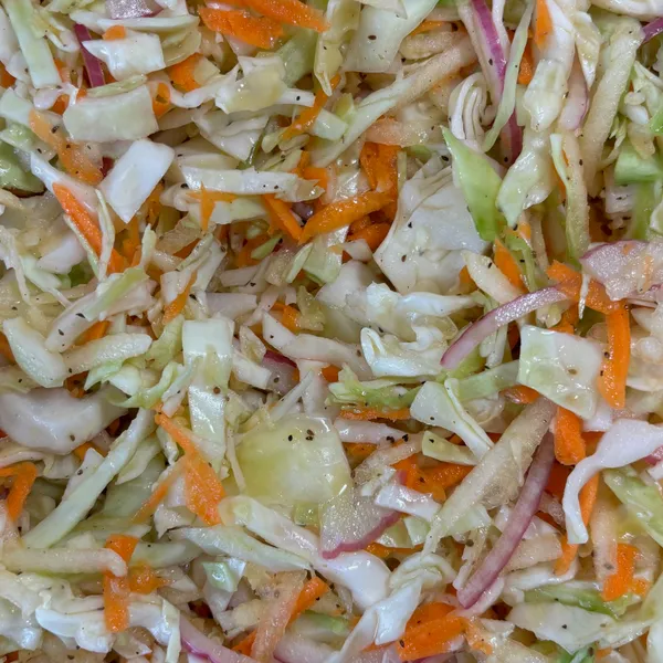 A pulled pork sandwich piled high with coleslaw and pickles
