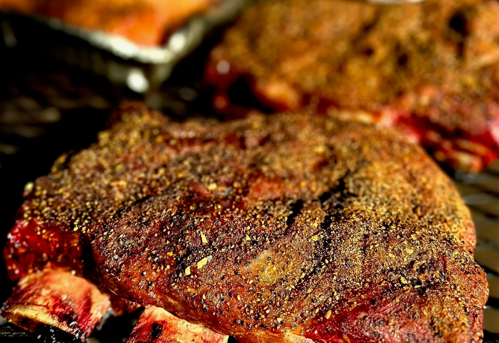 A rack of wood-smoked ribs with a peppery bark, fresh off the smoker in the sun