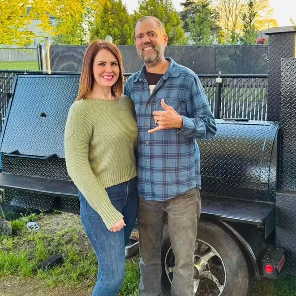 The Vanderwolf Smoke BBQ owners in front of their smoker trailer